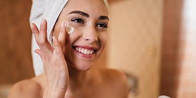 Woman applying moisturizer to face