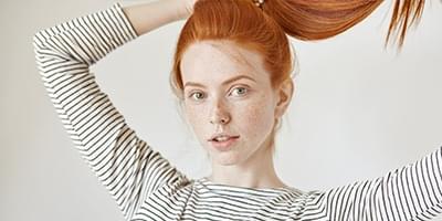 Red head woman with freckles playing with hair