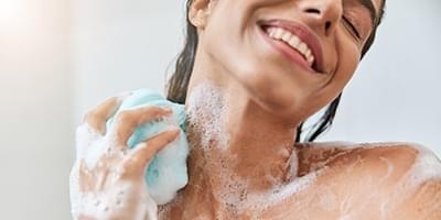 Woman scrubbing her neck with a loofah 