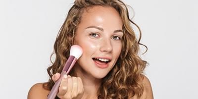 Woman applying makeup brush to face