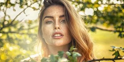 Woman with freckles in the sun looking at camera