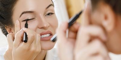 Woman putting on eyeliner