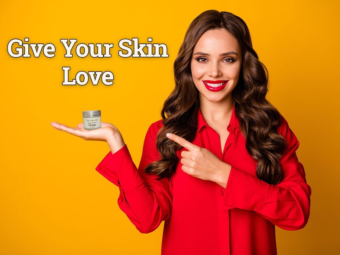 Woman pointing at jar of Tallow Balm That Reads "Give Your Skin Love