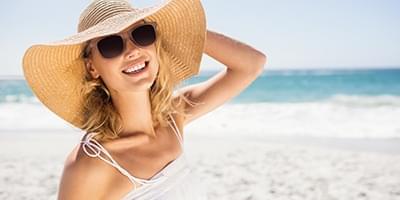 Woman posing at the beach with sunglasses and straw hat