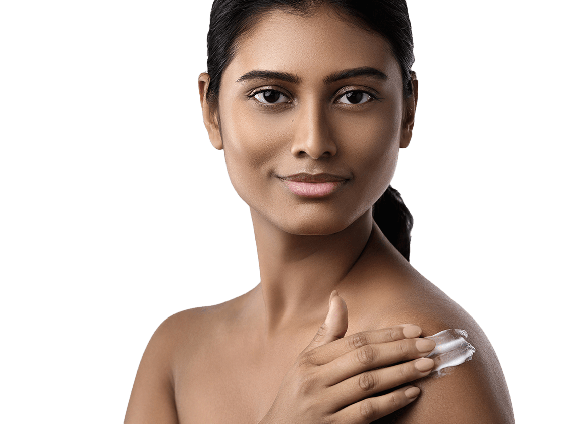Woman smiling and rubbing moisturizer on her shoulder